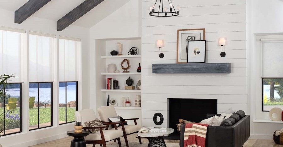 A bright, decorated living room includes motorized shades on the windows. Outside is an ocean view.  