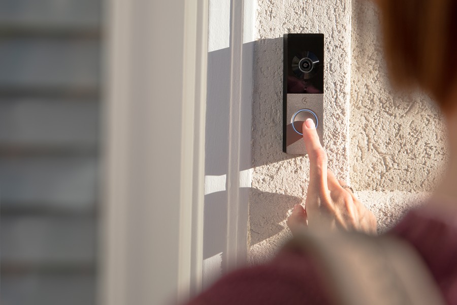 Hand pressing a doorbell that connects to a Control4 intercom system.