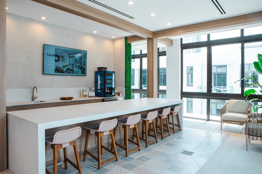 A luxury apartment building common area with a 4K display behind a coffee bar. 