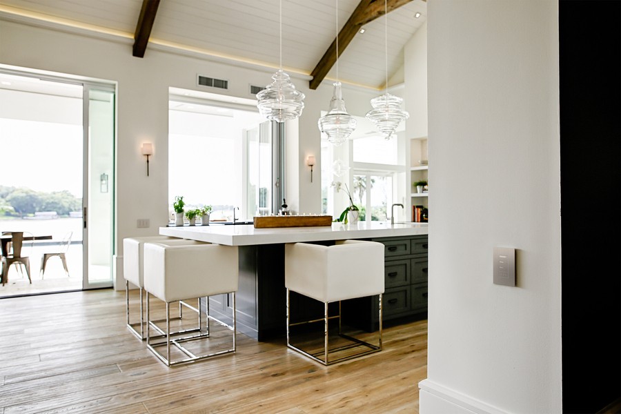 A bright, white kitchen and dining area with a Lutron lighting keypad on the wall. 