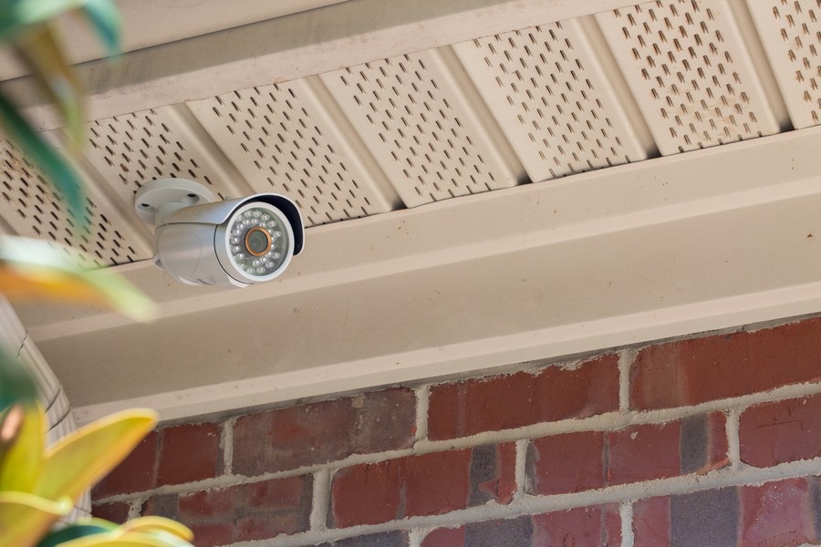 A close-up on a Luma outdoor security camera installed on the eave of a brick house. 