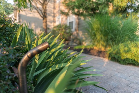  A Coastal Source lighting fixture mounted outside by a pathway.